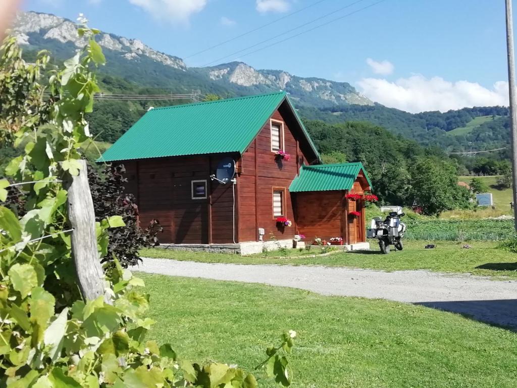 un granero con techo verde y montañas al fondo en KOLIBA A&A, en Kolašin