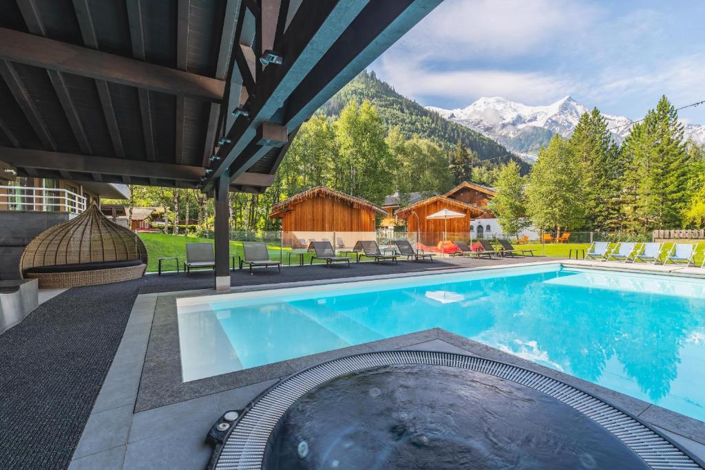 a swimming pool with a pool table and chairs at Hôtel Le Refuge des Aiglons in Chamonix