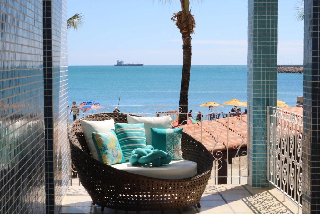 een rieten stoel op een balkon met uitzicht op het strand bij Sonho de Iracema Hostel Boutique in Fortaleza