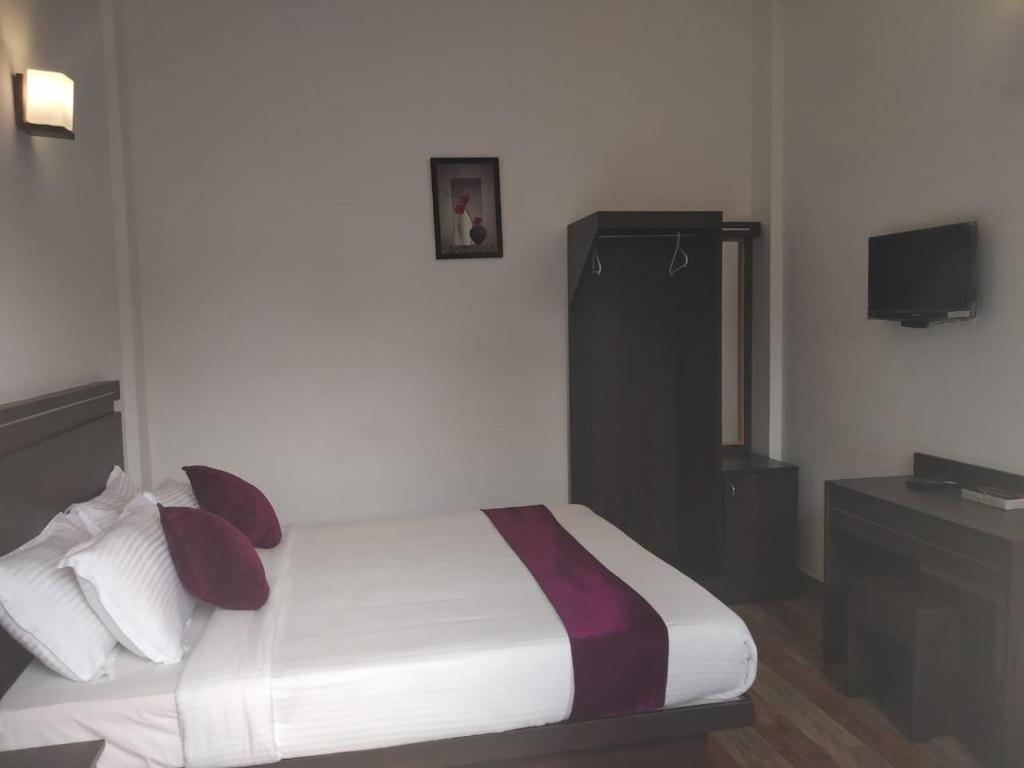 a bedroom with a bed with pillows and a television at Landy Queen in Munnar