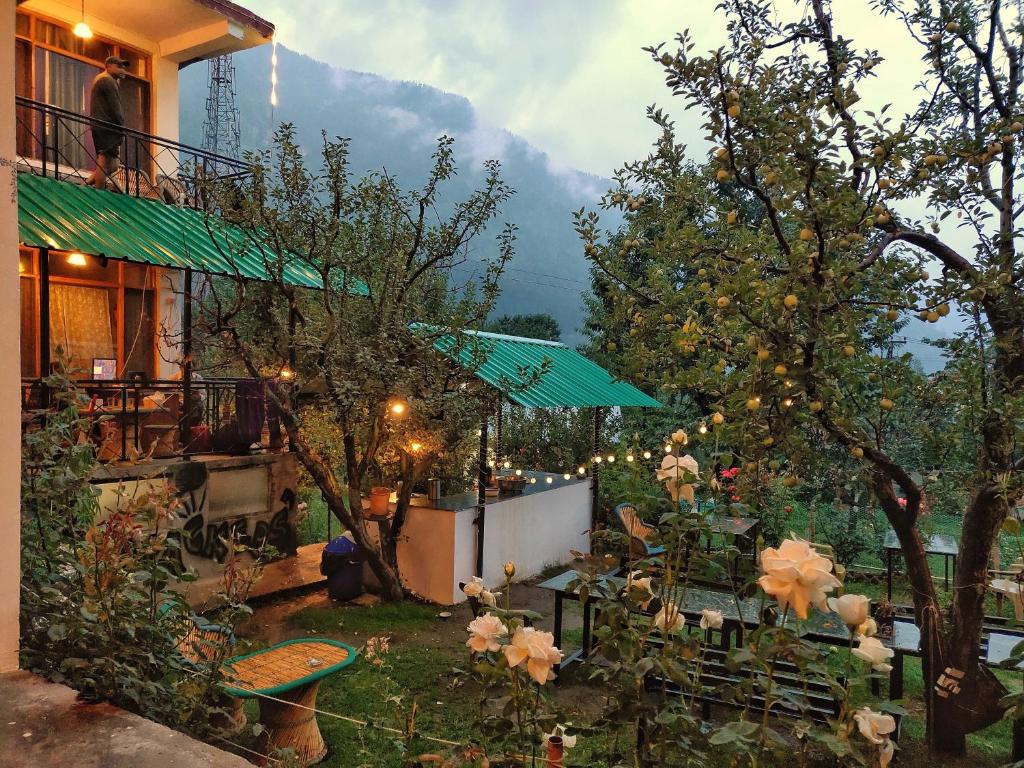 a garden with a house with a table and chairs at Madpackers Manali in Manāli