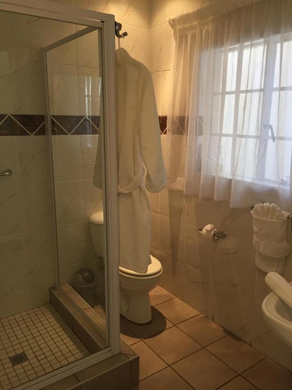 a bathroom with a toilet and a shower with a mirror at Welcome Guest House in Vereeniging