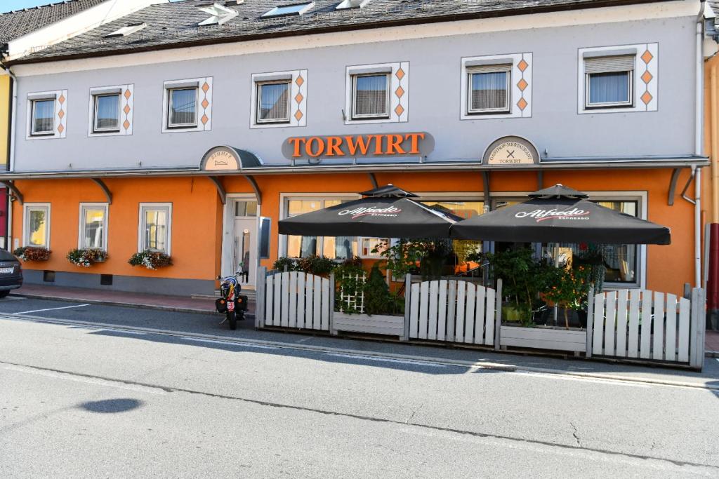 a hotel with two umbrellas in front of a building at Gasthof Torwirt in Lavamünd