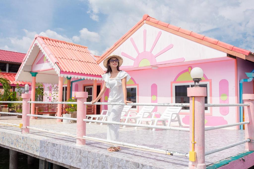 une femme debout devant une maison rose dans l'établissement Jamesbond Bungalow Koh Panyee, à Ko Panyi