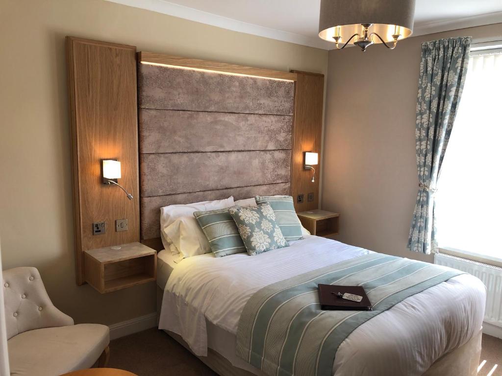 a bedroom with a large bed with a large headboard at Edgcumbe Guest House in Plymouth