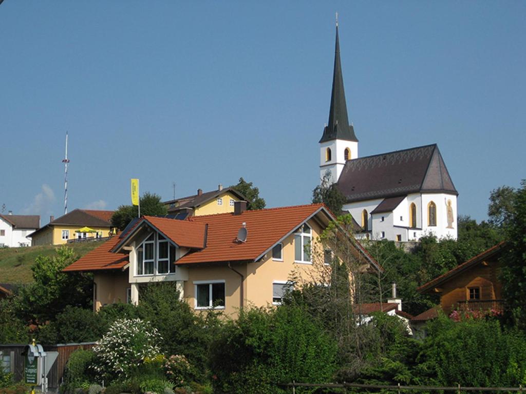 una iglesia sentada en la cima de una colina con una casa en Thaller Edeltraud, en Taching am See