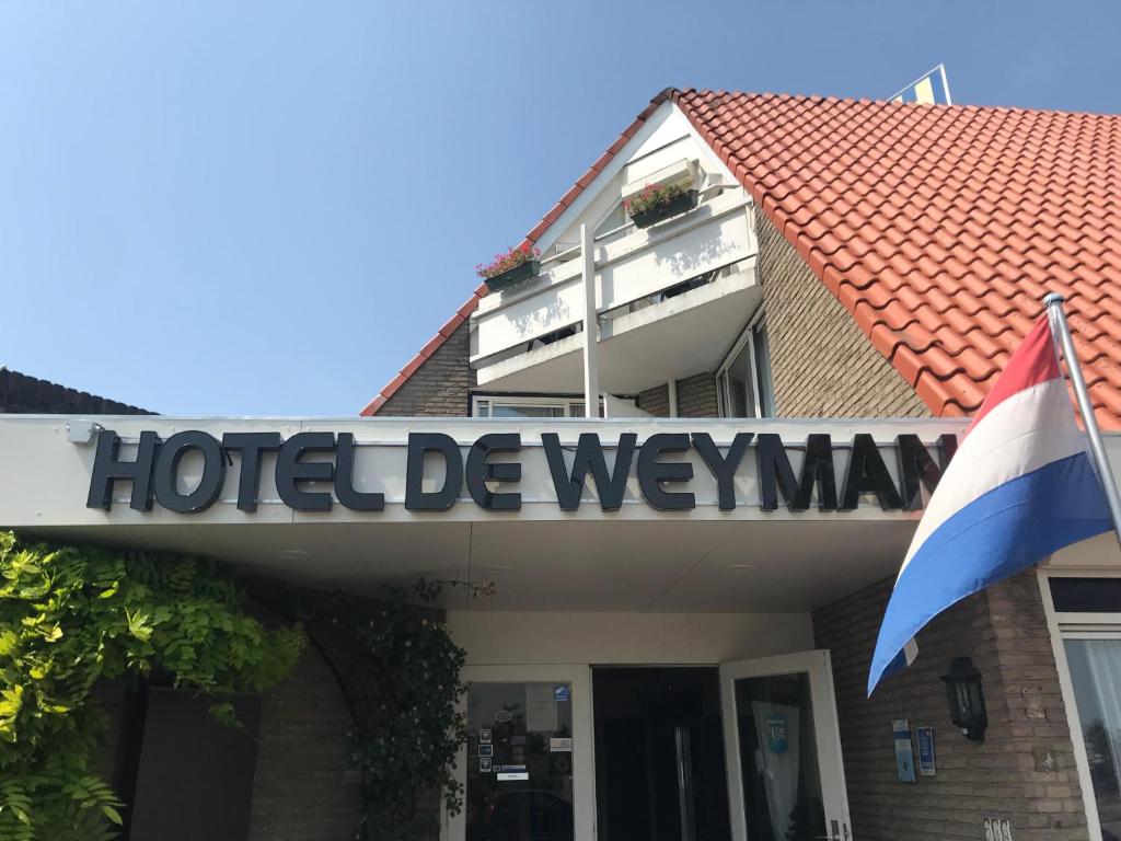 ein Hotel-Deweymann-Schild auf einem Gebäude mit einer Flagge in der Unterkunft Hotel De Weyman in Santpoort-Noord