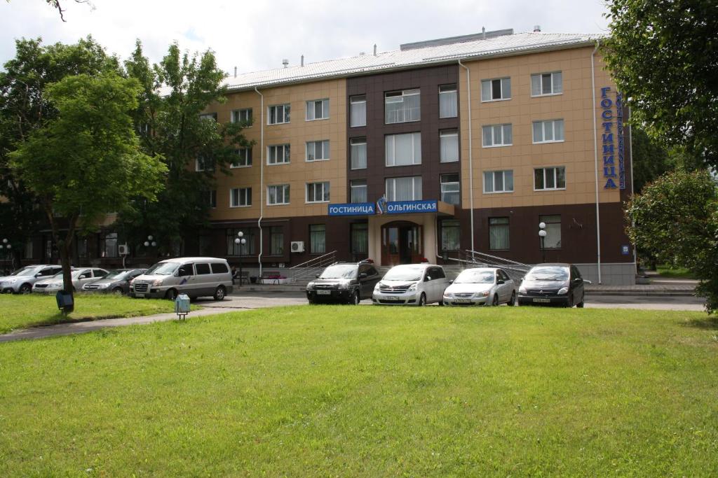 a building with cars parked in a parking lot at Olginskaya Hotel in Pskov