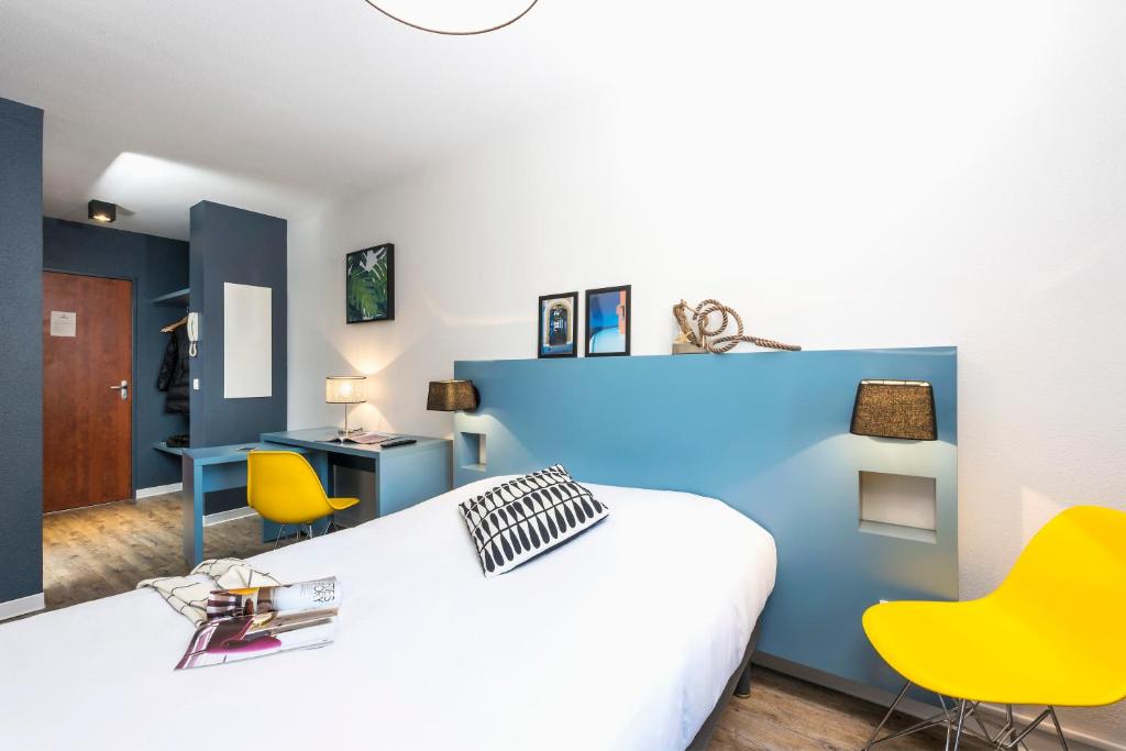 1 dormitorio con 1 cama blanca y sillas amarillas en Ténéo Apparthotel Bordeaux - Gare Saint Jean, en Burdeos