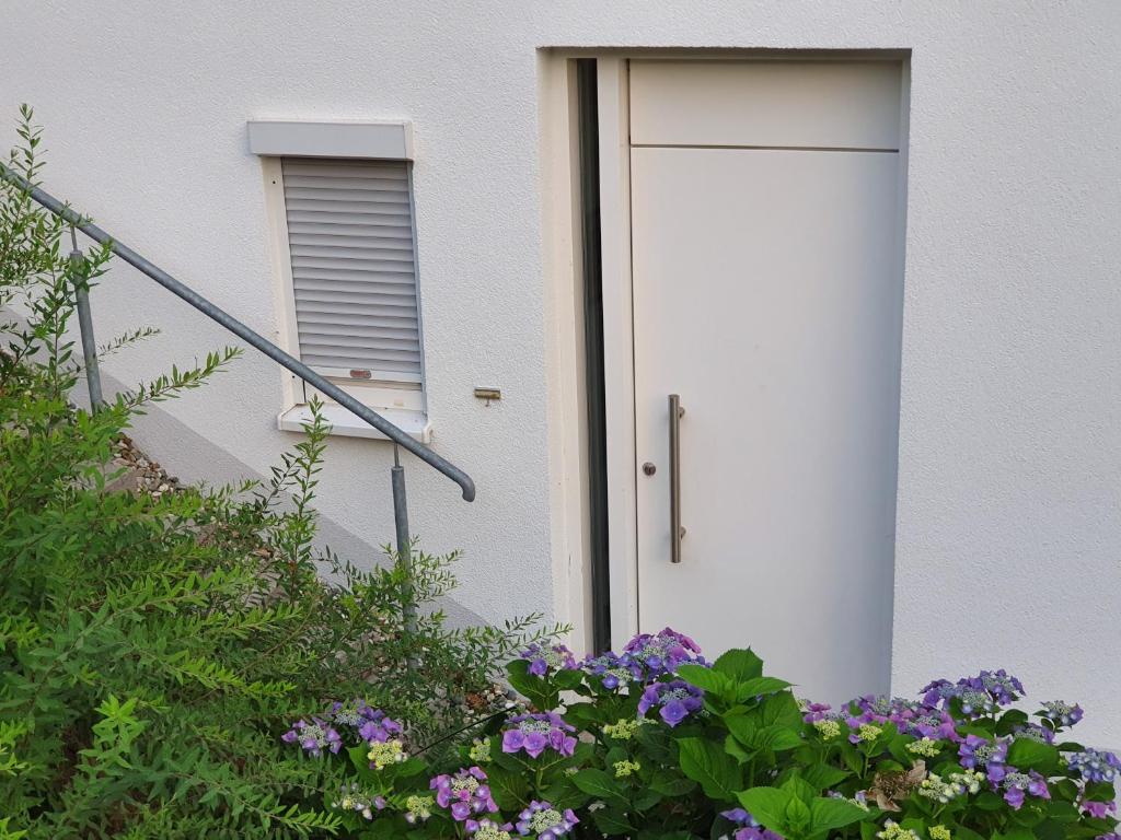 a white door on a building with purple flowers at Urlaubs(t)raum in Heiligkreuzsteinach