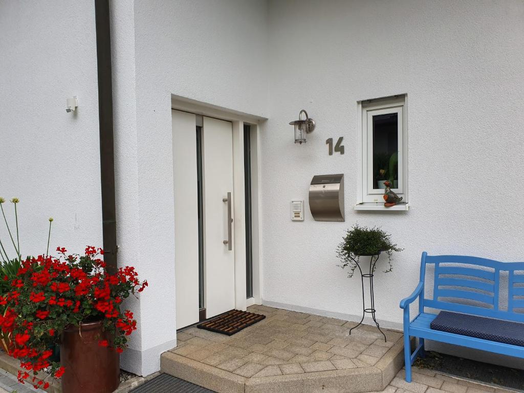 a porch with a blue bench and flowers and a door at Urlaubs(t)raum in Heiligkreuzsteinach