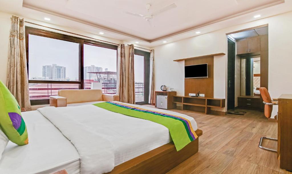 a bedroom with a large bed and a television at Treebo Trend Amexx Residency Sector 27 in Gurgaon