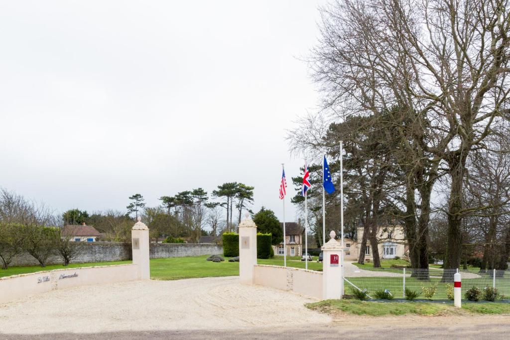 a park with two flags and a fence at Les Villas d'Arromanches, Teritoria in Arromanches-les-Bains