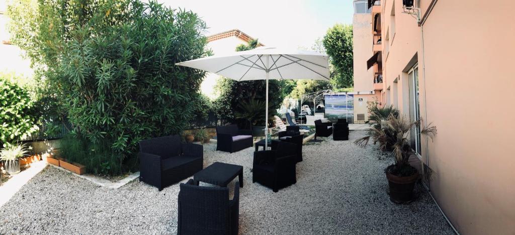 a patio with chairs and an umbrella in a courtyard at Resothel Le Gabian in Saint-Laurent-du-Var