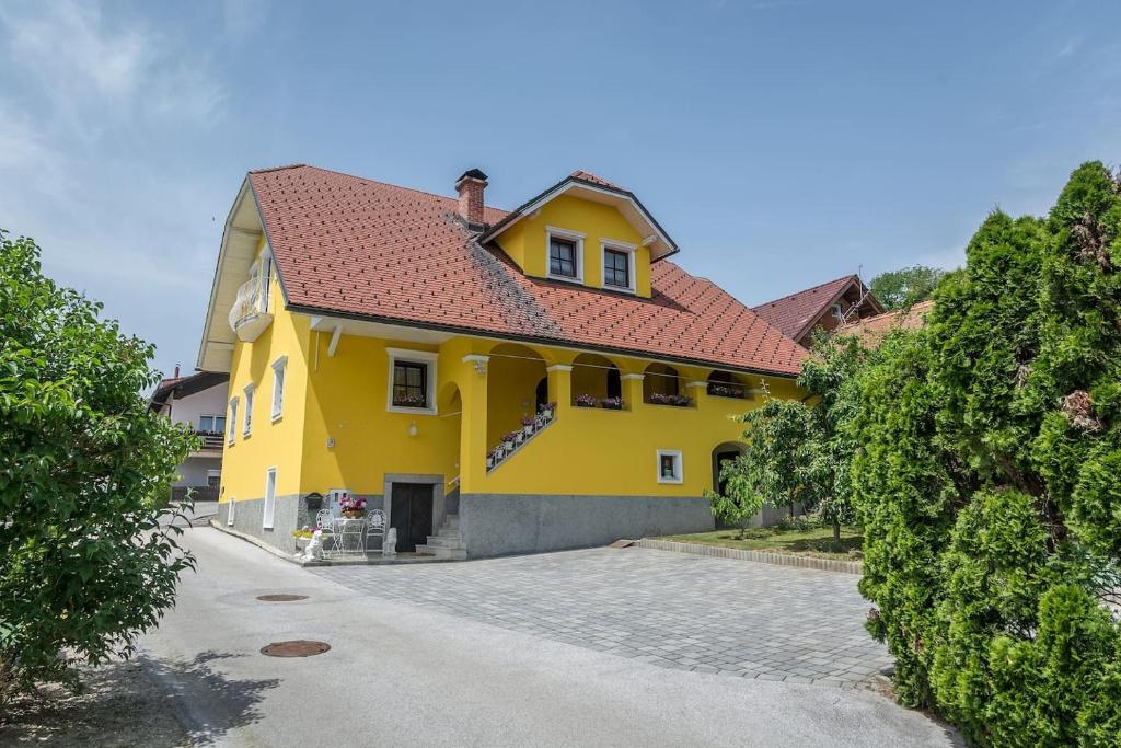 une maison jaune avec un toit rouge dans l'établissement APARTMA AJDA, à Komenda
