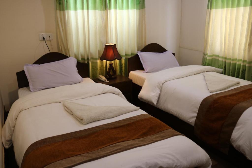 Cette chambre comprend 2 lits jumeaux et une lampe. dans l'établissement Kathmandu Peace Guesthouse, à Katmandou