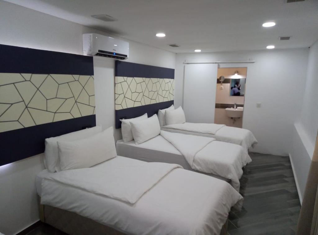 een kamer met 4 bedden en witte kussens bij Jardim das Acácias in Maputo