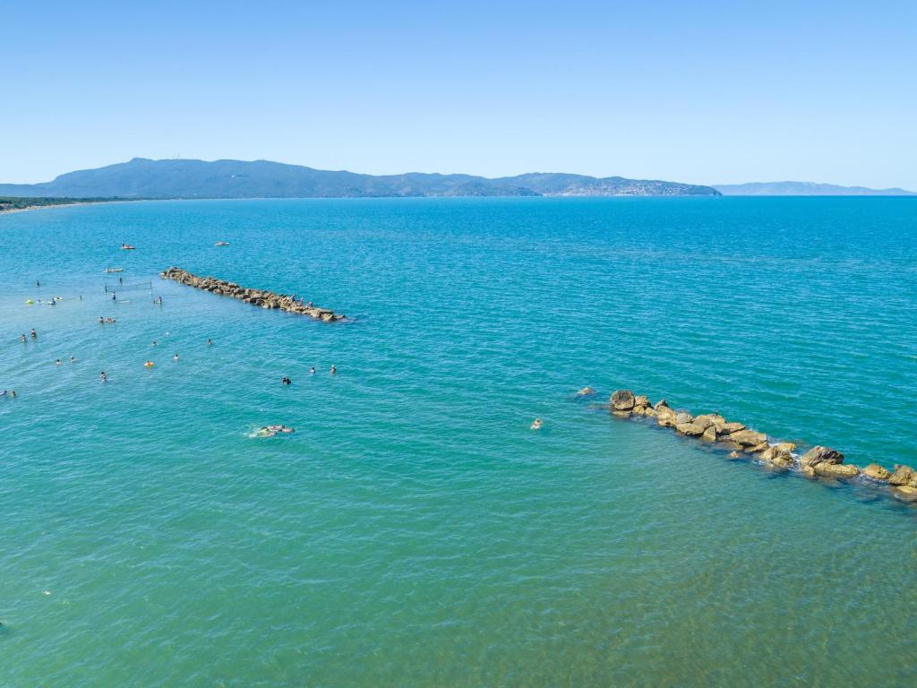 un gruppo di persone che nuotano in un grande corpo d'acqua di Argentario Garden House ad Albinia