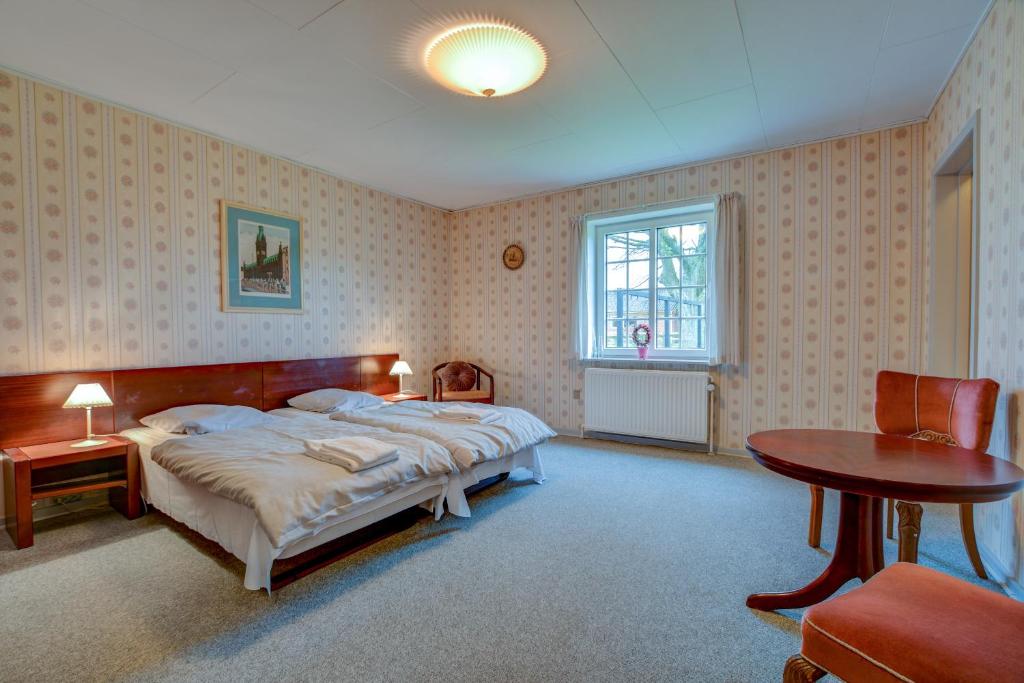Schlafzimmer mit einem Bett, einem Tisch und einem Fenster in der Unterkunft Abild Kro & Hotel in Tønder