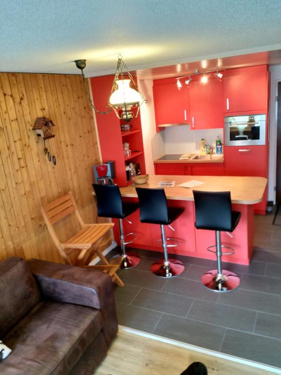 eine Küche mit roten Schränken sowie einem Tisch und Stühlen in der Unterkunft Haus Opal,Wohnung Nr.25 in Grächen