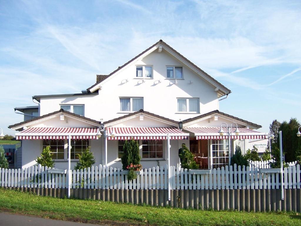 a white house with a white picket fence at Hotel am Kirschberg in Alten Buseck