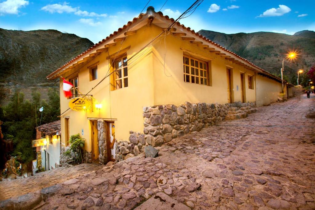 a house on a stone road next to a building at Parwa Guest House in Ollantaytambo