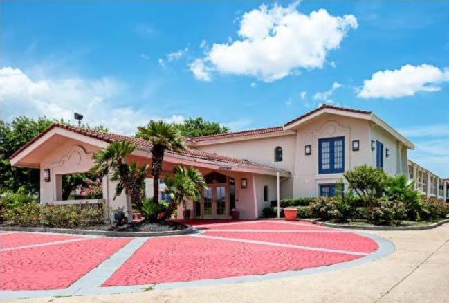 una casa con una alfombra roja delante de ella en Scottish Inns & Suites, en Texas City