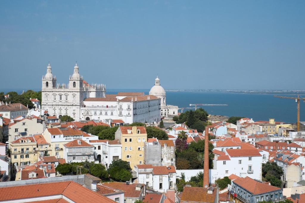 Castle Lisbon Typical في لشبونة: اطلاله على مدينه بها مباني و مياه