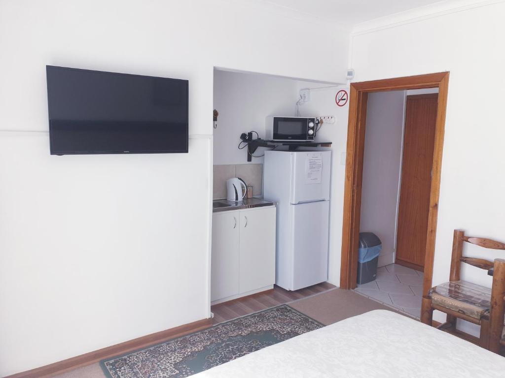 a room with a kitchen and a television on a wall at Sunflower Self-Catering in Walvis Bay