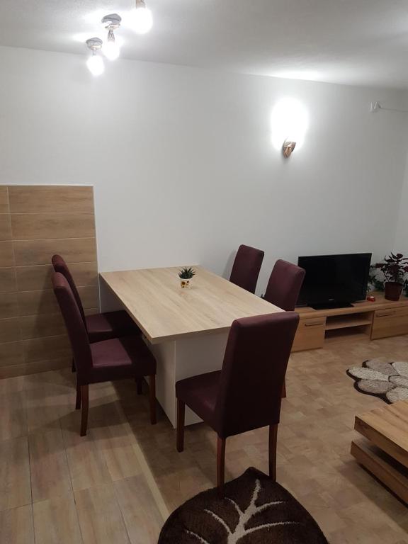 une salle à manger avec une table, des chaises et une télévision dans l'établissement Apartment Centar LUX, à Banja Luka
