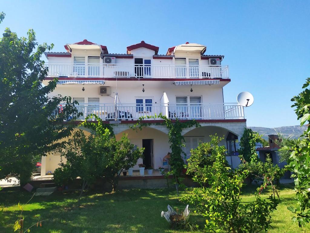Cette grande maison blanche dispose d'un balcon et d'arbres. dans l'établissement Apartmant Sučić, à Kaštela