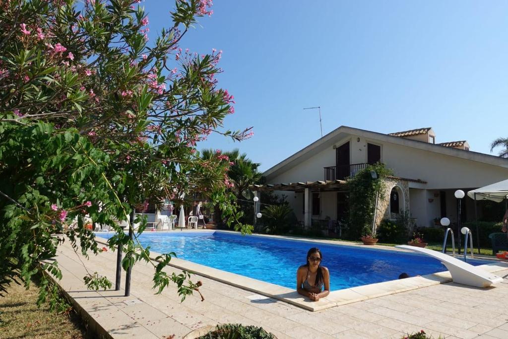 una mujer sentada junto a una piscina en Casa di Costanza e Flavia en Punta Secca