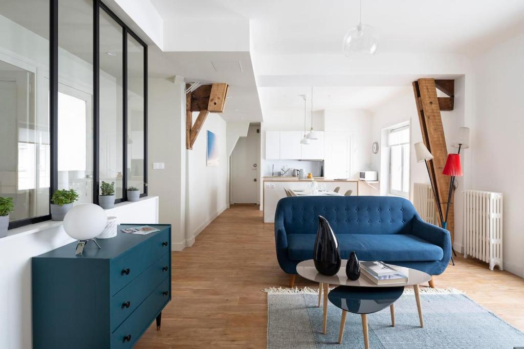 ein Wohnzimmer mit einem blauen Sofa und einem Tisch in der Unterkunft Harmonie by Cocoonr in Nantes
