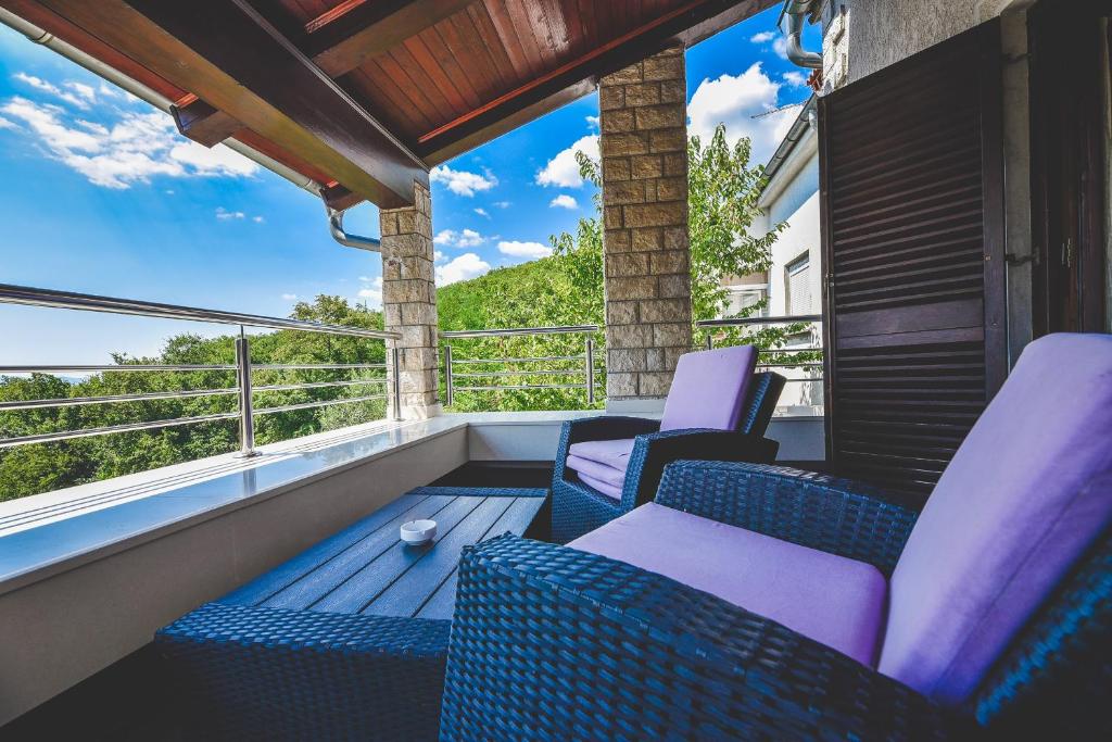 uma varanda com cadeiras e vista para as montanhas em Apartment and Room Tacy em Opatija