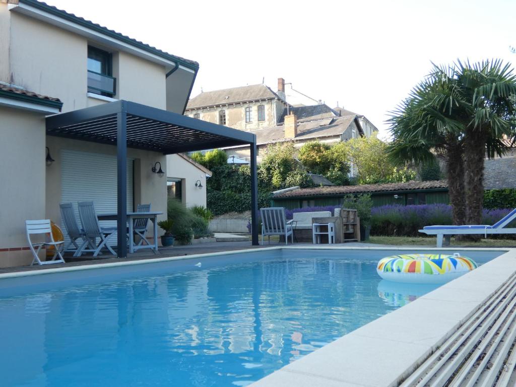 a swimming pool with a pergola next to a house at Villa du Vicomte in Thouars