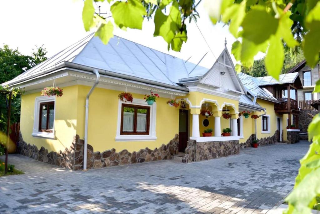 a yellow house with a tile roof at Căsuța de Poveste in Târgu Neamț