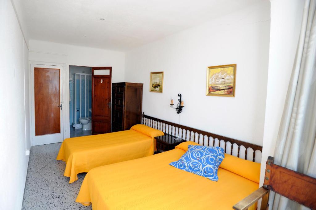 two beds in a room with yellow sheets at Hostal Can Marinés in Sant Carles de la Ràpita