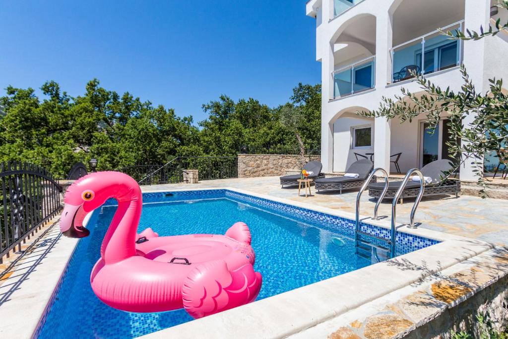 una piscina con flamencos rosas inflables frente a una casa en Dolaca Villas en Sutomore
