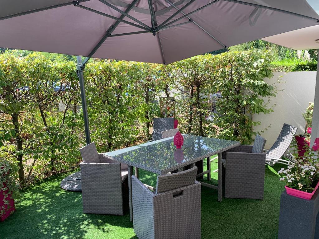 - une table et des chaises sous un parasol dans le jardin dans l'établissement Royal Standing- Terrasse & Parking Privé, à Évian-les-Bains
