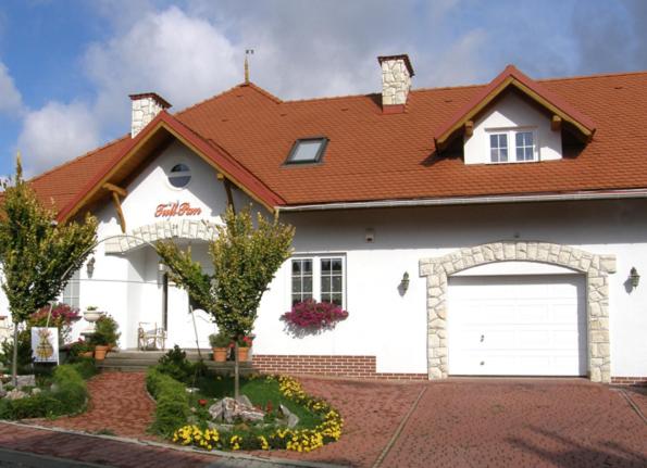 a white house with a red roof and a garage at Dom Tulipan in Krynica Zdrój