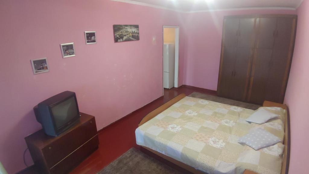um pequeno quarto com uma cama e uma televisão em квартира на вулиці Лесі Українки em Uzyn
