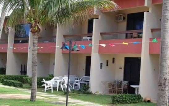 a hotel with tables and chairs in front of a building at Apartamento em frente Mar in Salvador