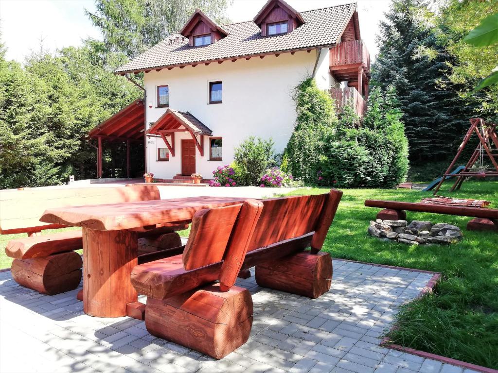 a picnic table and benches in front of a house at Harmonia in Karpacz