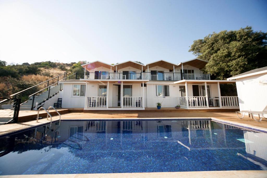 a house with a swimming pool in front of a house at Metins Gümüşlük in Bodrum City