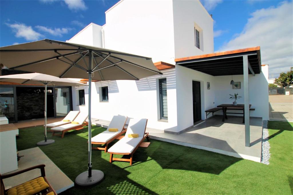 an outdoor patio with chairs and an umbrella at Holiday House and Spa Lanzarote in Tías