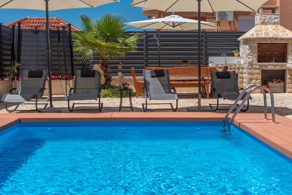 a swimming pool with chairs and an umbrella at Apartment Maja with private pool in Sveti Petar