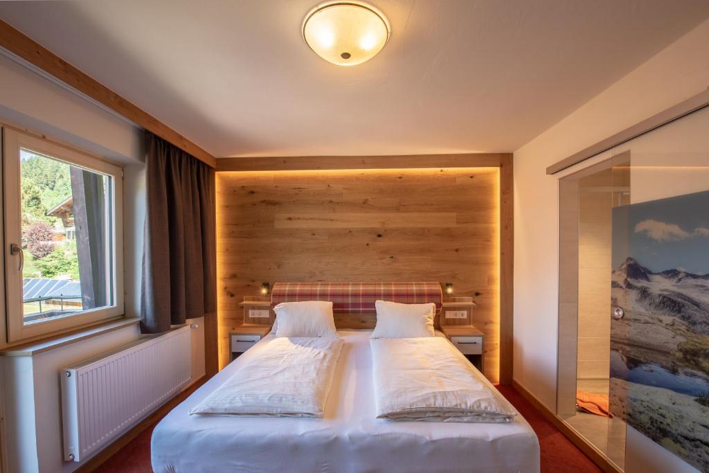 a bedroom with a large white bed with a window at Hölzl Bed & Breakfast in Neukirchen am Großvenediger