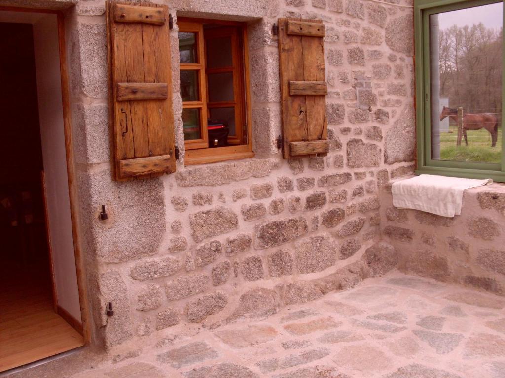un bâtiment en pierre avec une fenêtre et un cheval à l'extérieur dans l'établissement ESCALE NATURE, à Saint-Angel
