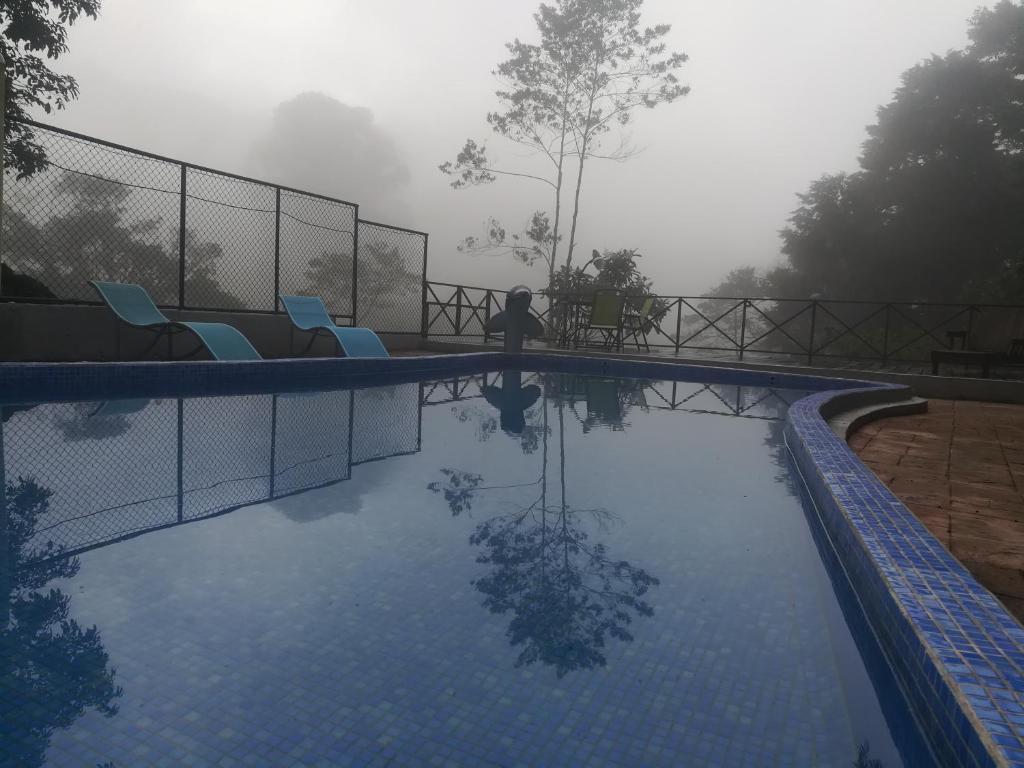 a swimming pool with chairs and a person standing next to it at Quinta los volcanes in Turrialba