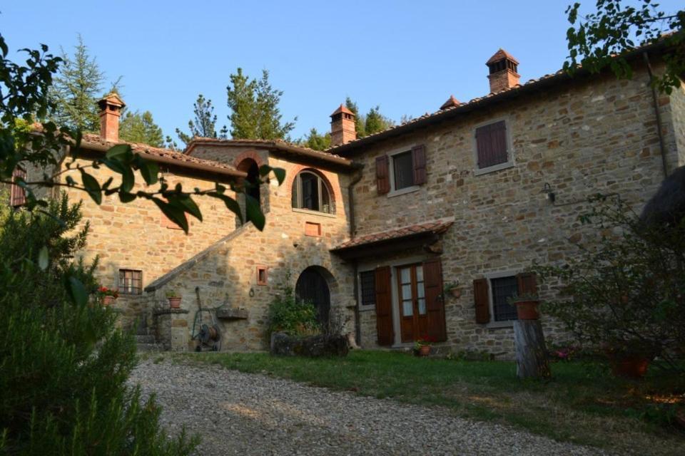 una antigua casa de piedra con un edificio en Podere Spinabbio en Castiglion Fiorentino